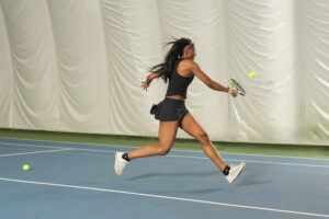 A female athlete practicing indoors to boost her USTA tennis rating.