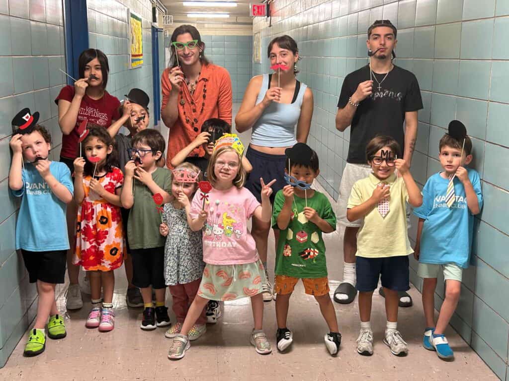 Summer camp counselors and camp-goers acting silly with fun props.