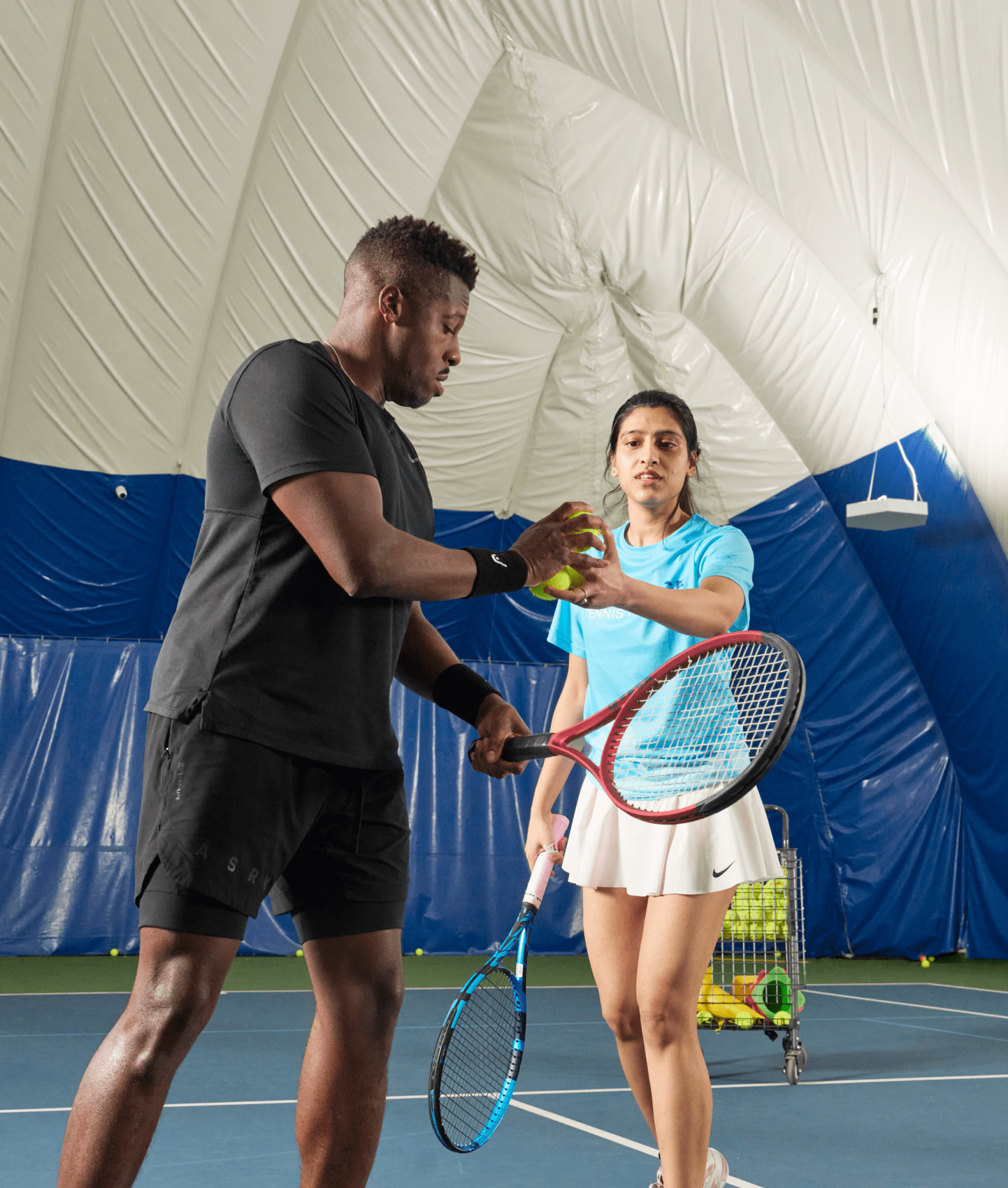 A group of NYC adults learning to play tennis on an indoor court.