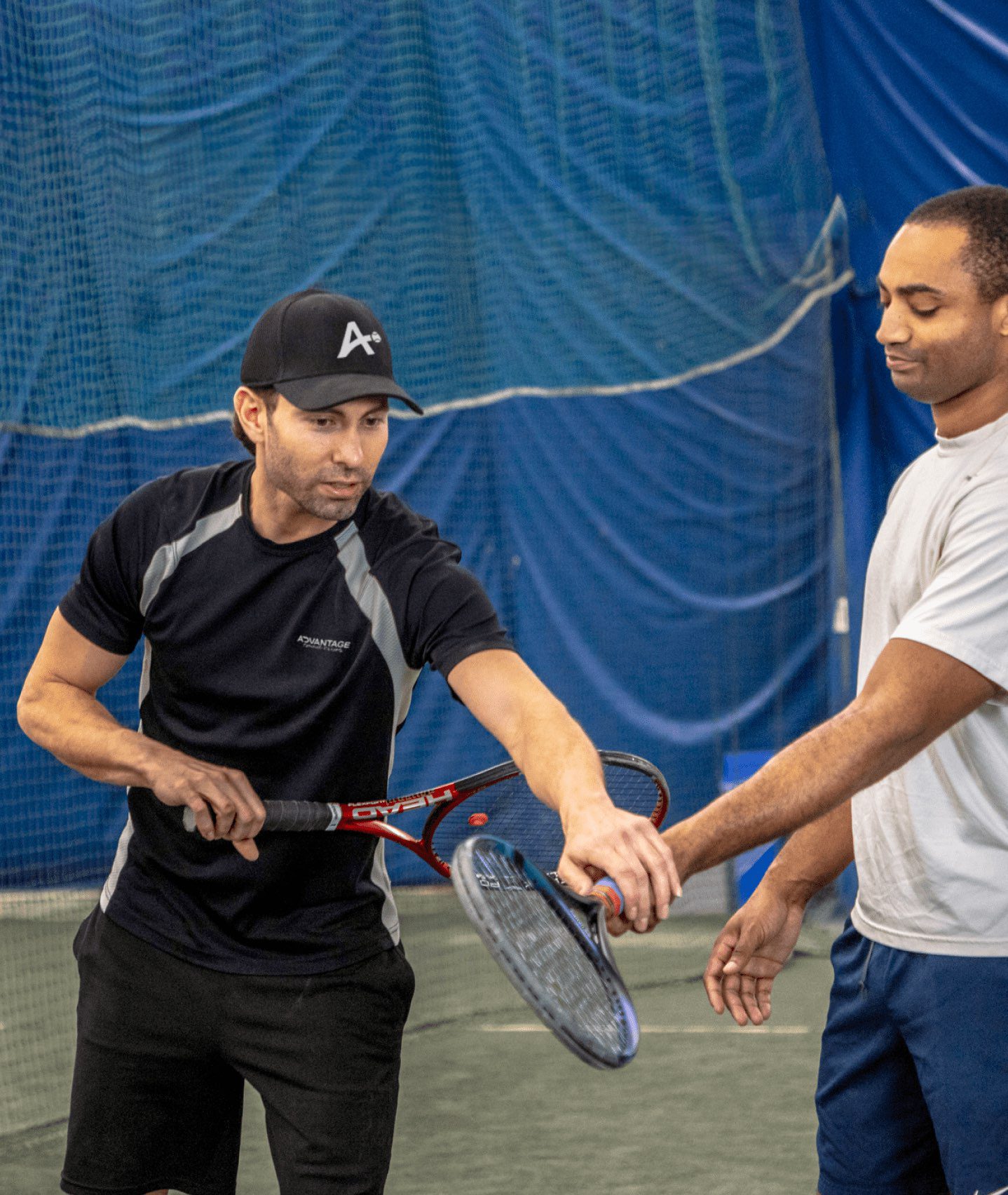 careers-lesson A pro in a tennis coaching position shows a junior player how to hold a racket to serve.