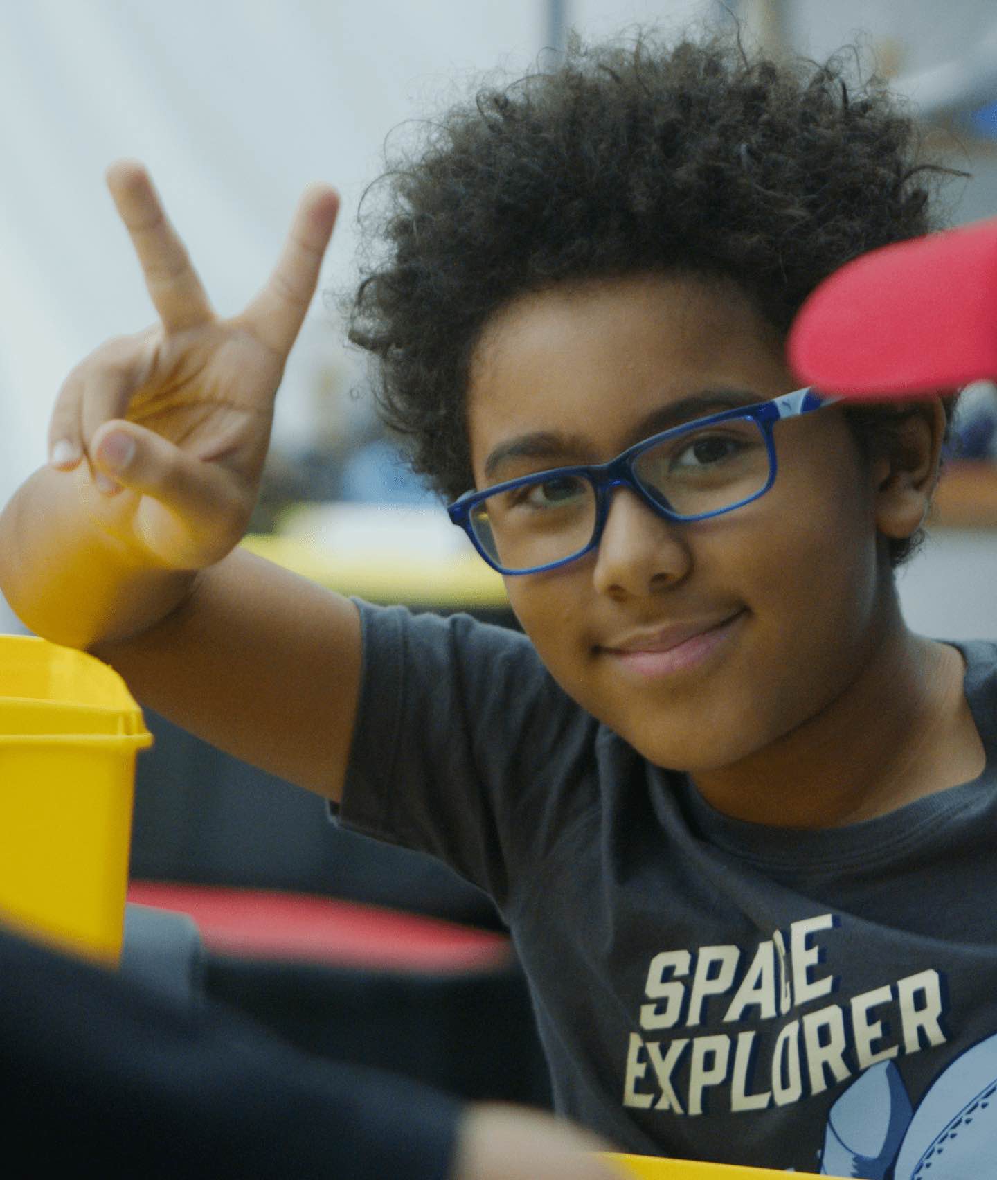 stem-science-day camp A smiling boy flashes a peace sign while enjoying a summer science program in New York City.
