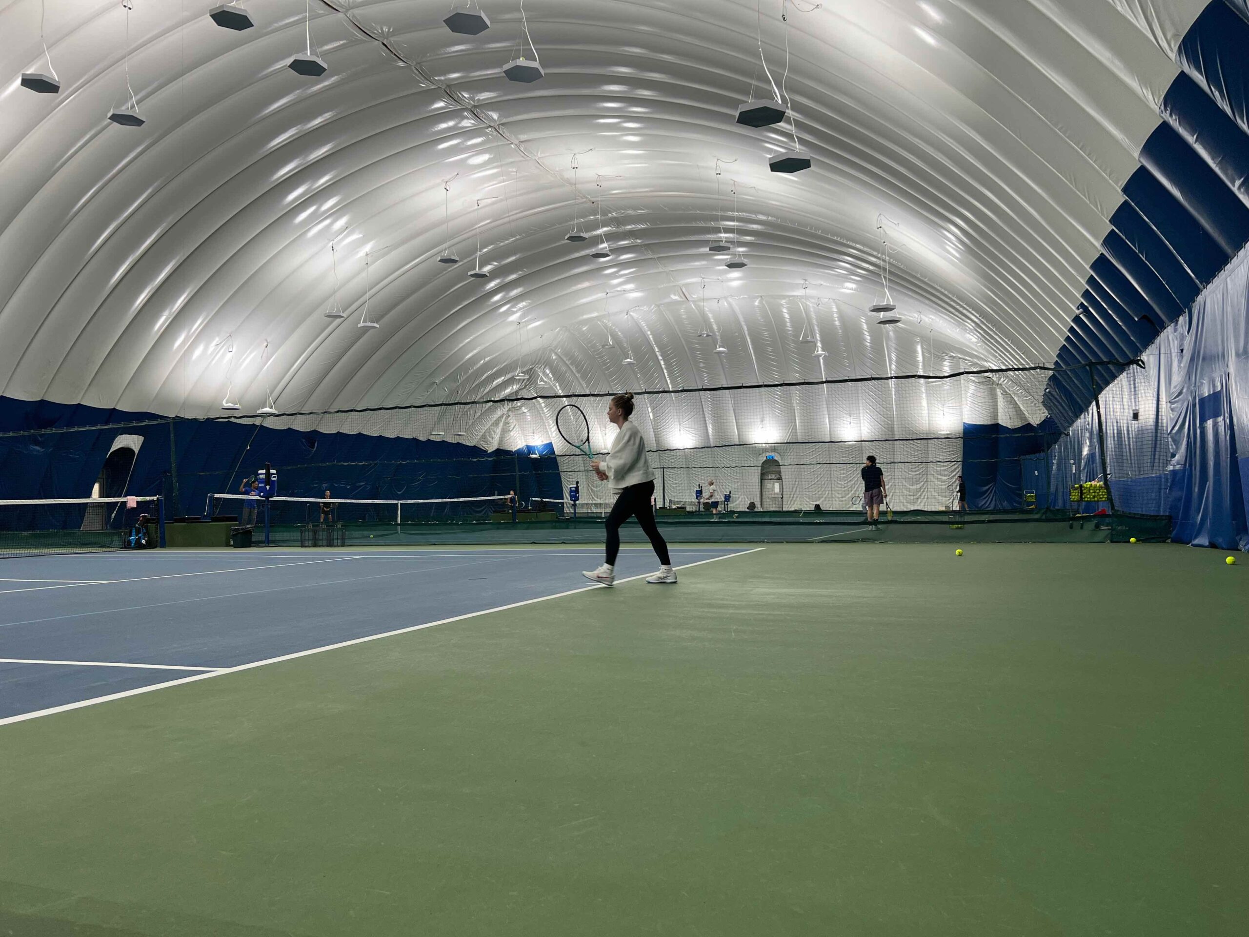 NYC Health Club Tennis A woman playing tennis inside a New York City health club and fitness complex.
