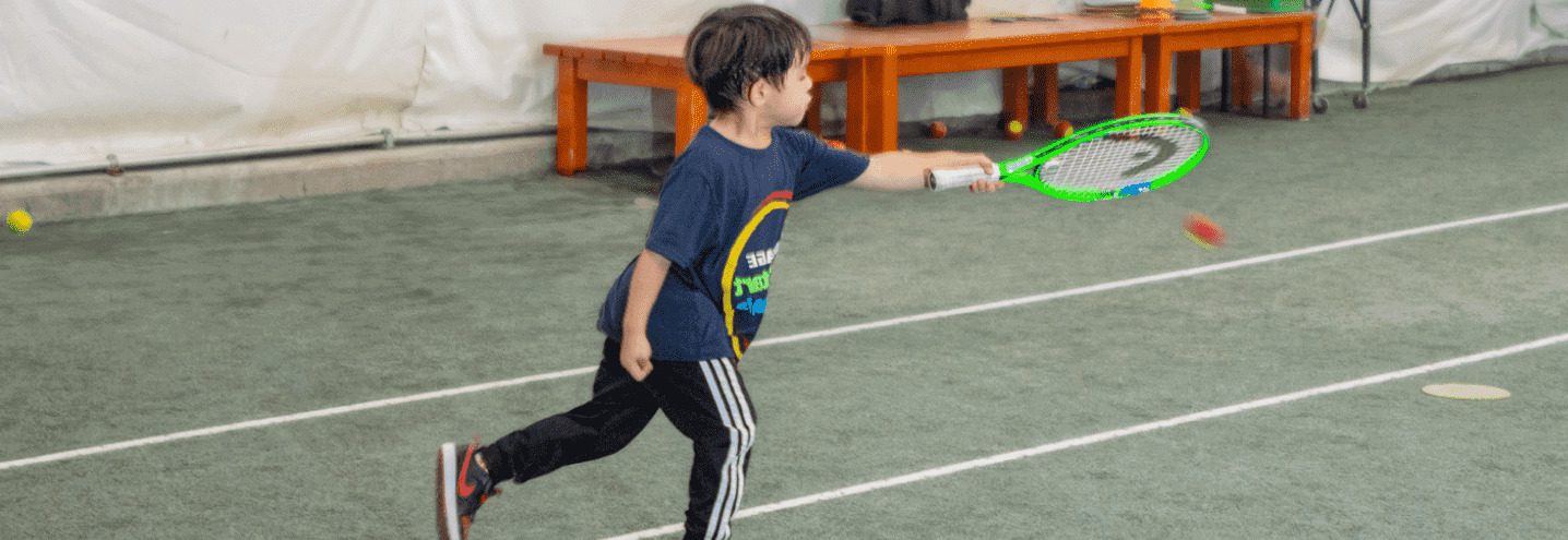Young boy hitting tennis ball